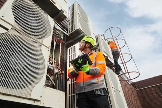 Técnico avaliando unidades condensadoras de um sistema de climatização em edifício comercial